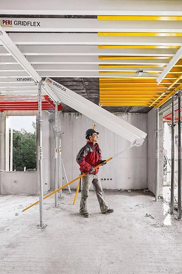 Worker positioning a PERI Gridflex formwork beam under a slab
